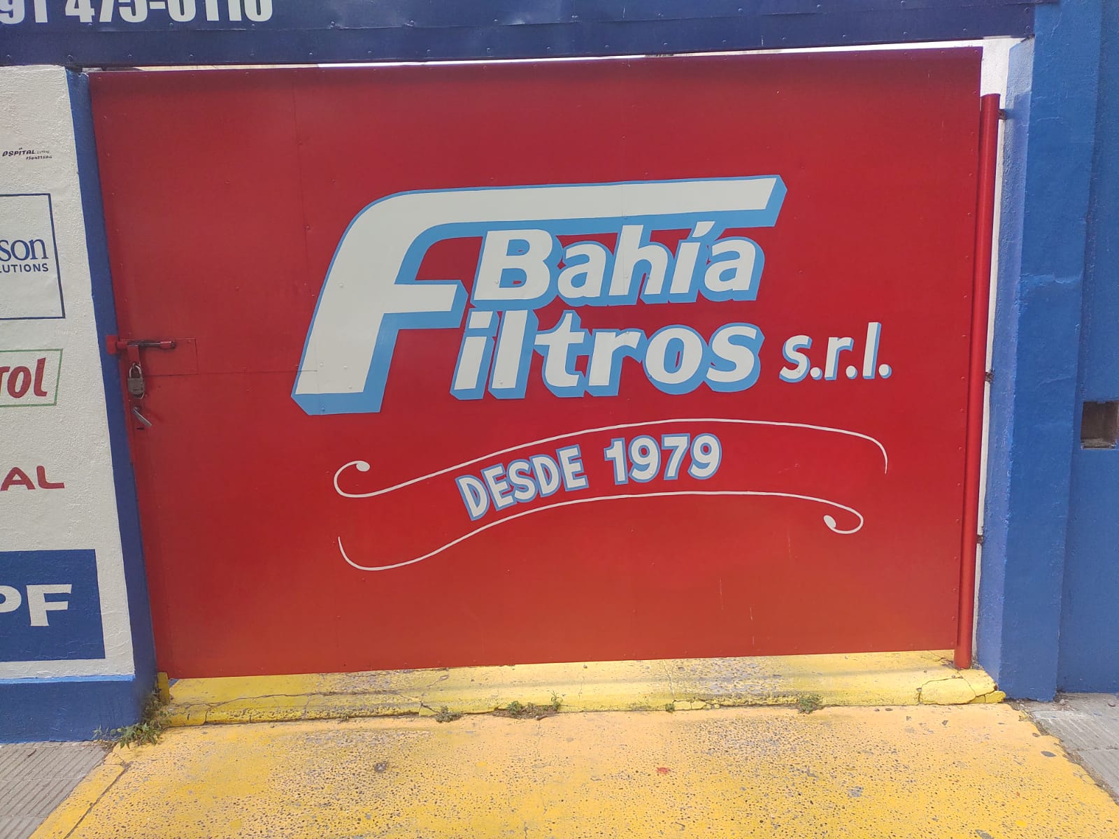 Portón rojo con el logo de Bahía Filtros y la leyenda Desde 1979